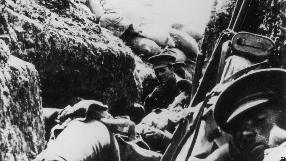 Soldiers wait in a trench