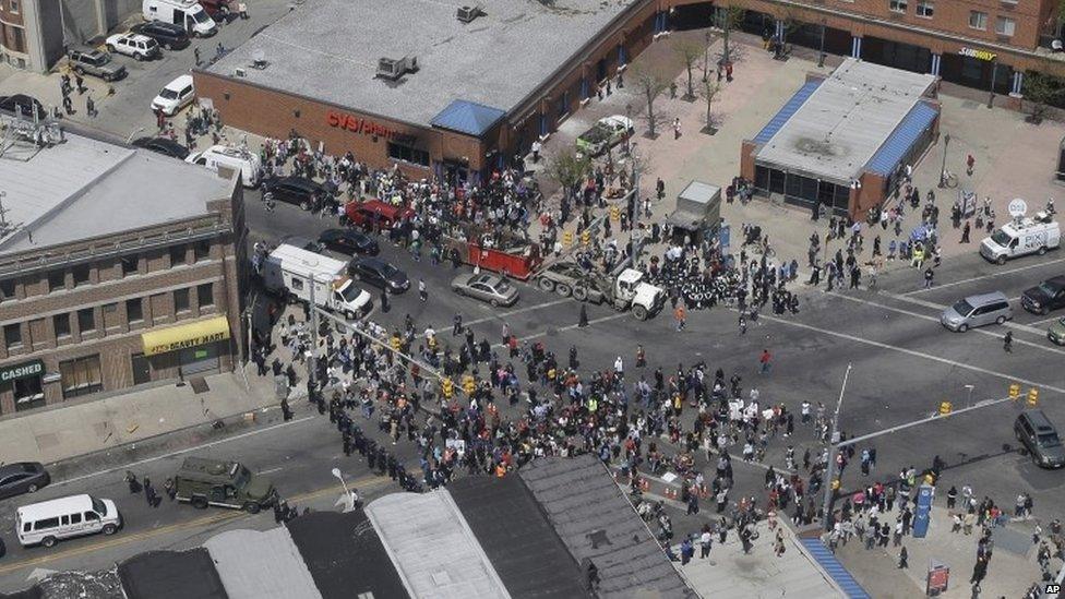 In this aerial photo, police stand in formation near a gathering of protestors at the intersection of North Avenue and Pennsylvania Avenue 28 April 2015