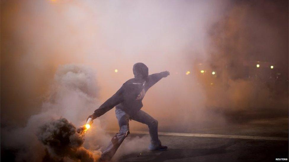 Protester throws gas canister at police