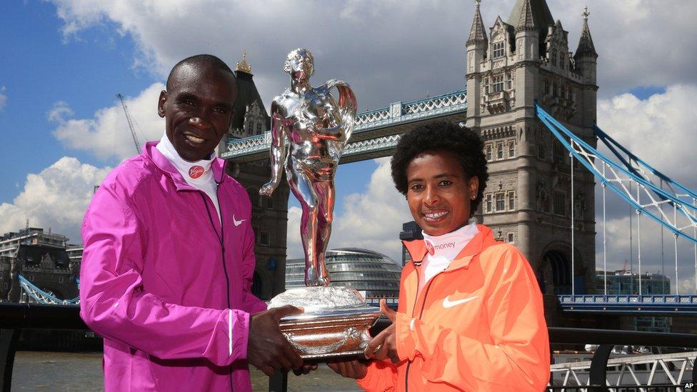 Marathon runners Eliud Kipchoge (l) of Kenya and Ethiopia's Tifgist Tufa (r) posing with a trophy in London, the UK - Monday 27 April 2015