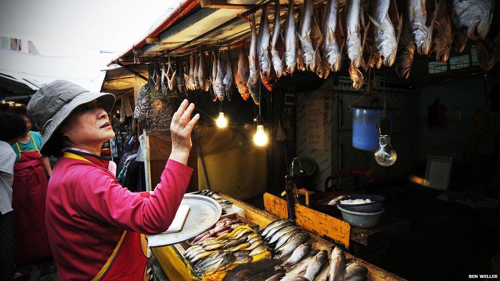 A vendor counts the fish at Busan's Oncheonjang market.