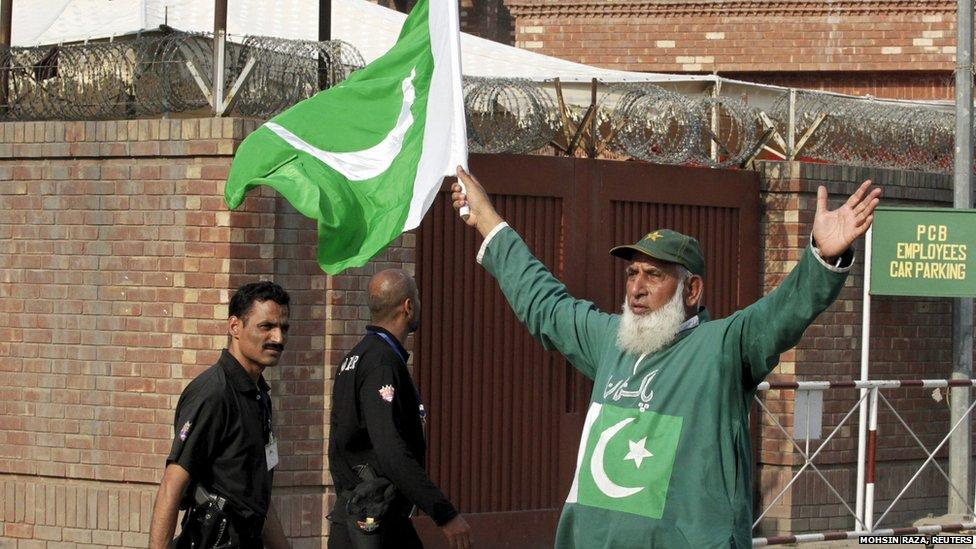 Policemen pass by a Pakistan cricket fan outside the Gaddafi Stadium in Lahore (19 May 2015)