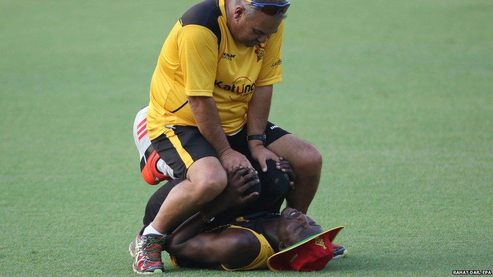 Zimbabwe's cricket team coach Dav Whatmore (top) helps player Chris Mpofu to stretch during a practice session in Lahore (20 May 2015)