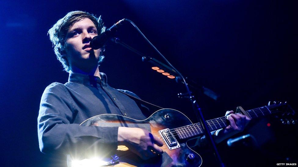 George Ezra performs on stage with a guitar