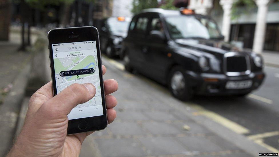 Uber app on the phone near London black cab