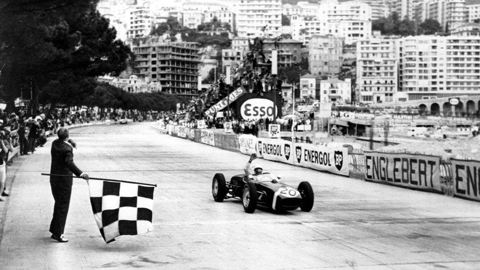 Stirling Moss of Britain raises his hand in victory after passing the finish line (and chequered flag) in first place at the Monaco Grand Prix Automobile race on May 14, 1961.