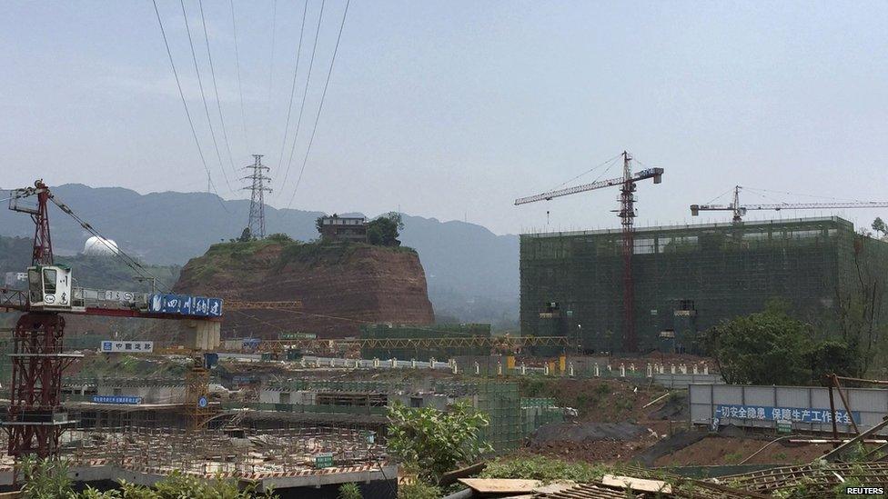 A nail house sits on top of a mound, next to a construction site for a new residential area, in Yibin, Sichuan province, China