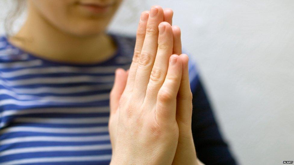 Woman makes "namaste" gesture of courtesy