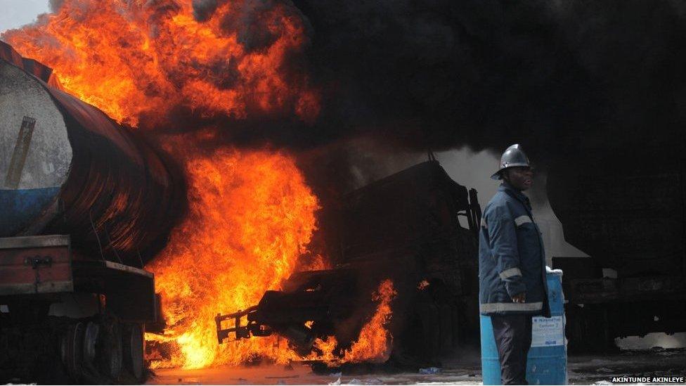 A fireman looks the other way as a fire burns in an oil tanker