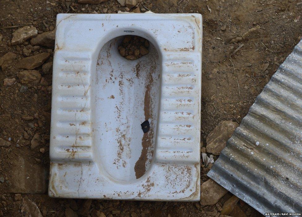 A toilet pan, surrounded by rubble