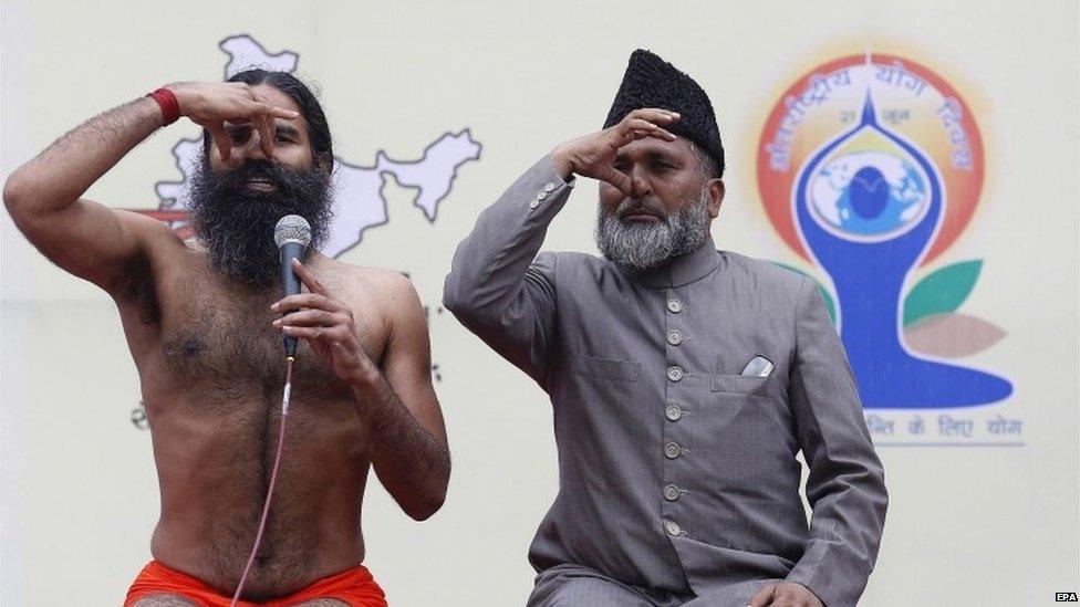 Indian yoga guru Baba Ramdev (L) and former All India Imams Organisation general secretary and now a former member of the India Against Corruption core committee, Mufti Shamoon Qasmi (R) during the Yoga rehearsal camp for the International Yoga Day in heavy rain at Jawaharlal All Nehru Stadium in New Delhi, 14 June 2015.