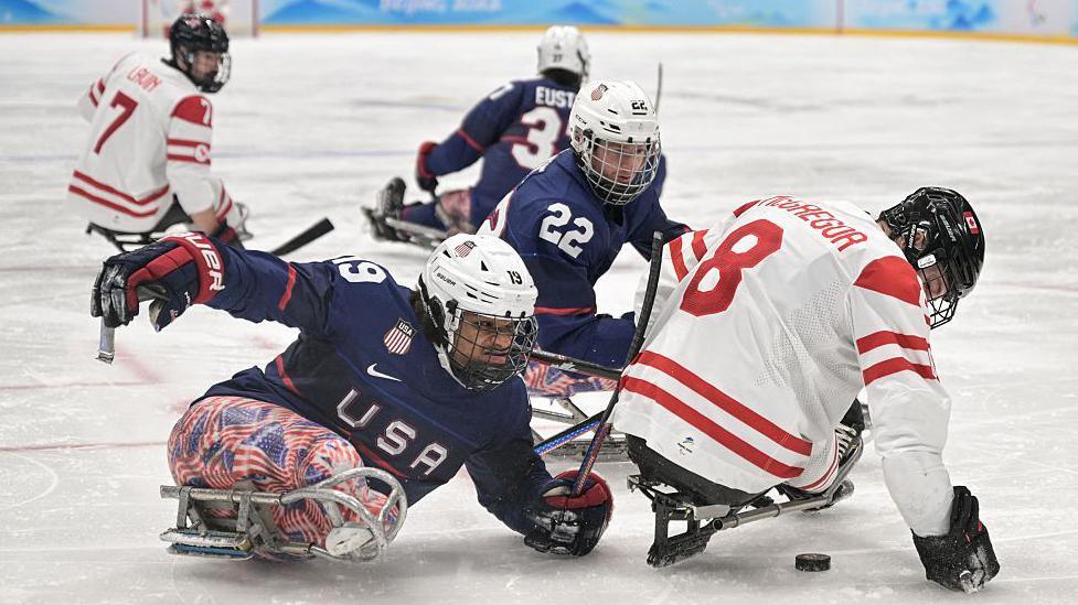 Malik Jones of the USA and Tyler McGregor of Canada battle for the puck in the Para-ice hockey final at the 2022 Winter Paralympics in Beijing 