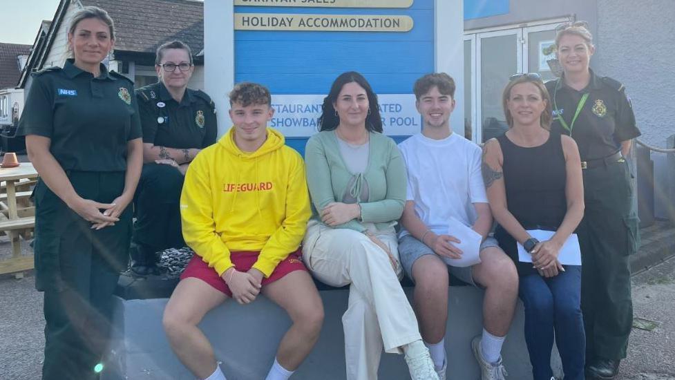 Secamb staff with staff at Romney Sands Holiday Park next to a holiday park sign