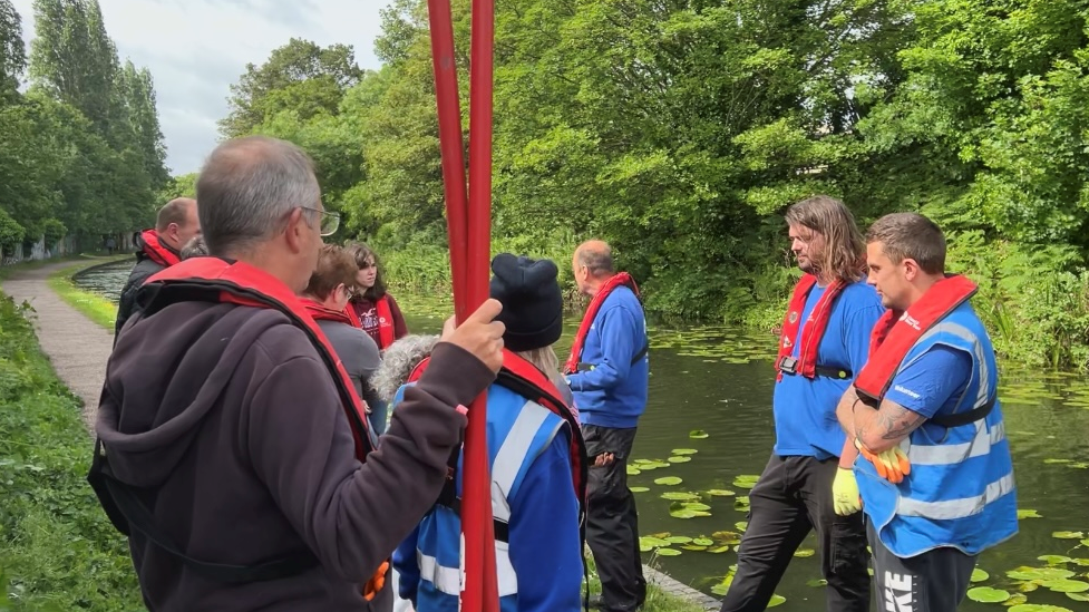Group of people in blue jumpers with red life jackets on standing in a circle like formation.