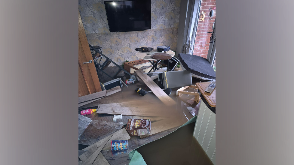 Flood water and furniture lie broken on the dining room floor.