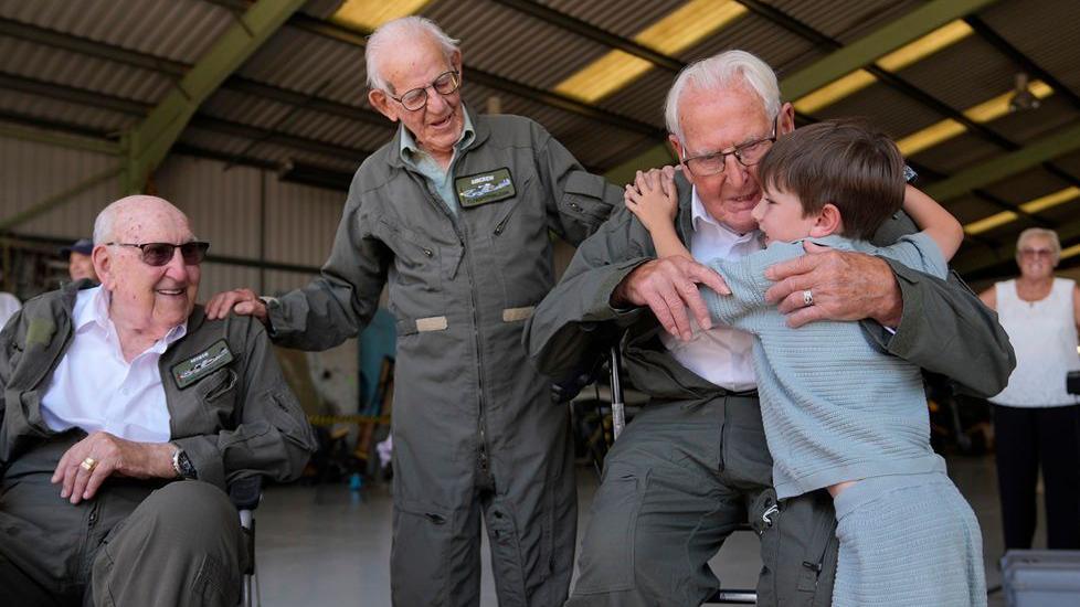 Second World War veteran Ivan Staines, 99, hugs his five-year-old great-grandson Alfie Rose inside a hangar at Biggin Hill Airport in Kent. Nearby, fellow veterans Alfred Cooley and Paul Terry wear flying suits as they prepare for their first Spitfire flights.