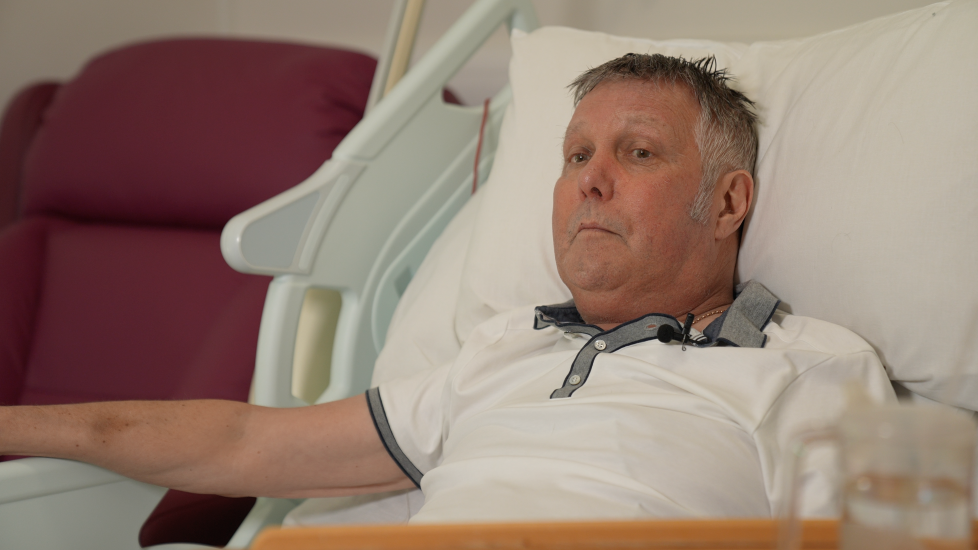 Jabez Petherick, who has short grey hair and is wearing a white polo shirt with grey collar while lying on a hospice bed.