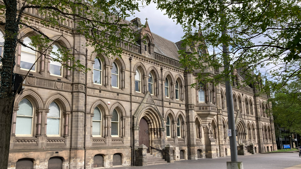 Middlesbrough Town Hall is a grand grey stone building with arched windows and a large wooden doors.