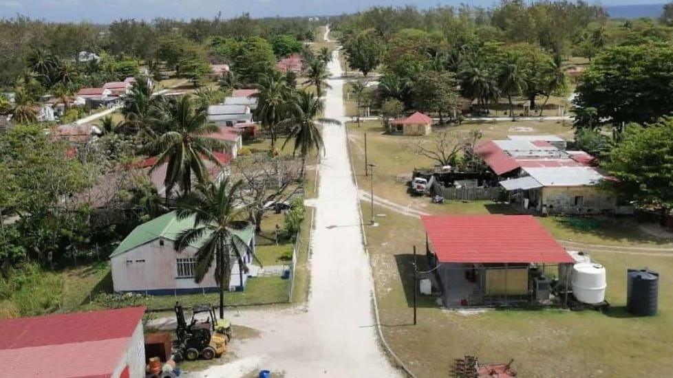 Agalega's biggest village Vingt-Cinq - there is a narrow white road with small, detached red tin-roofed houses on either side