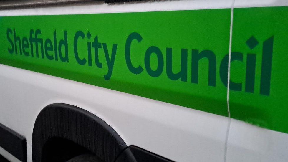 A white minibus has green writing along the side saying Sheffield City Council