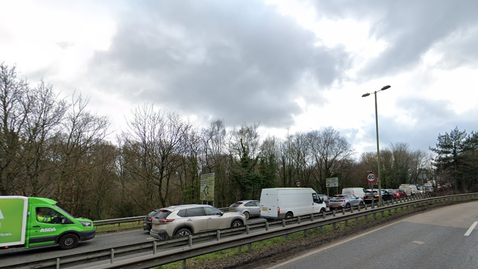 Cars and a van queueing on one side of the road on the approach to the Windhover Roundabout. There is a 40mph sign on one side of the road 