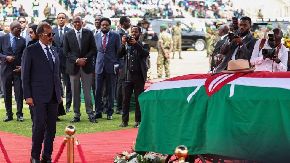 Somali President Hassan Sheikh Mohamud wearing a suit while standing near Odinga's casket 