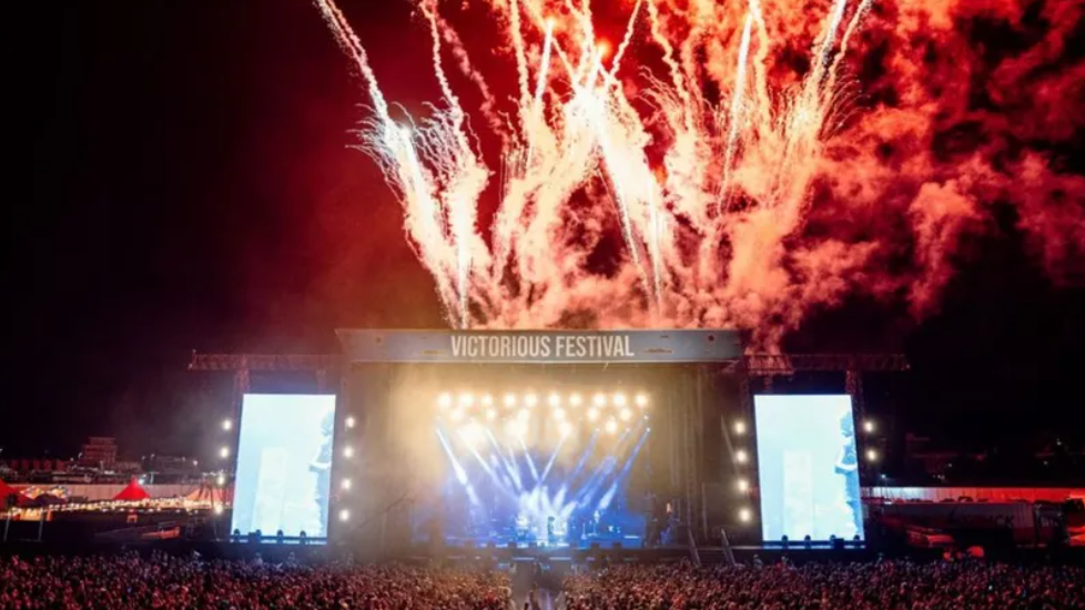 Main stage with crowds of people listening to music and watching fireworks.