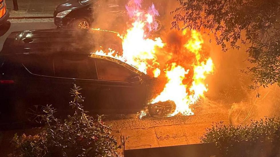 A still from a video showing a car on fire.
