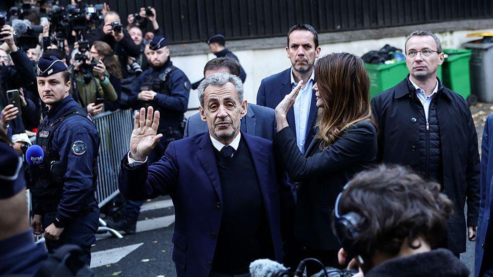 Former French President Nicolas Sarkozy and his wife wave at crowds and photographers on the street before he goes to prison