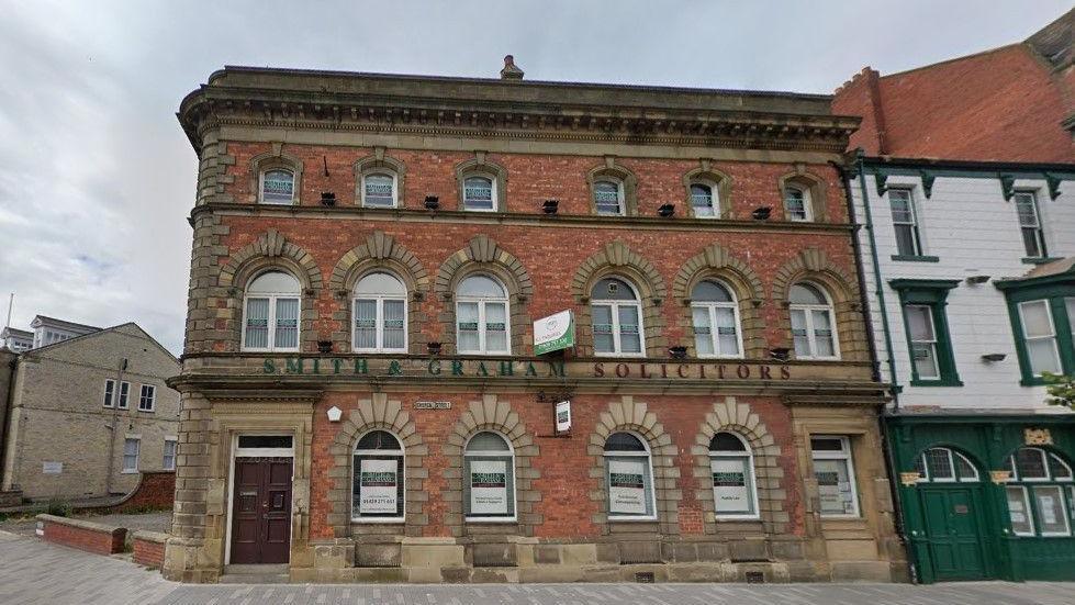 The building that previously housed Smith and Graham solicitors office. The three storey red-brick building has decorative arches around the windows and doors.