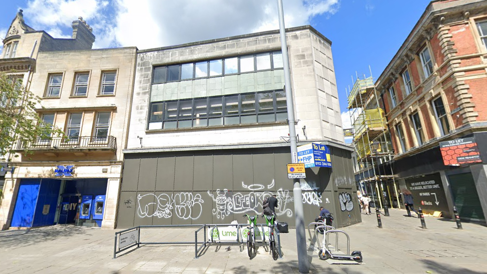 A Google Streetview showing the boarded up former McDonald's restaurant. The boarding has graffiti on.