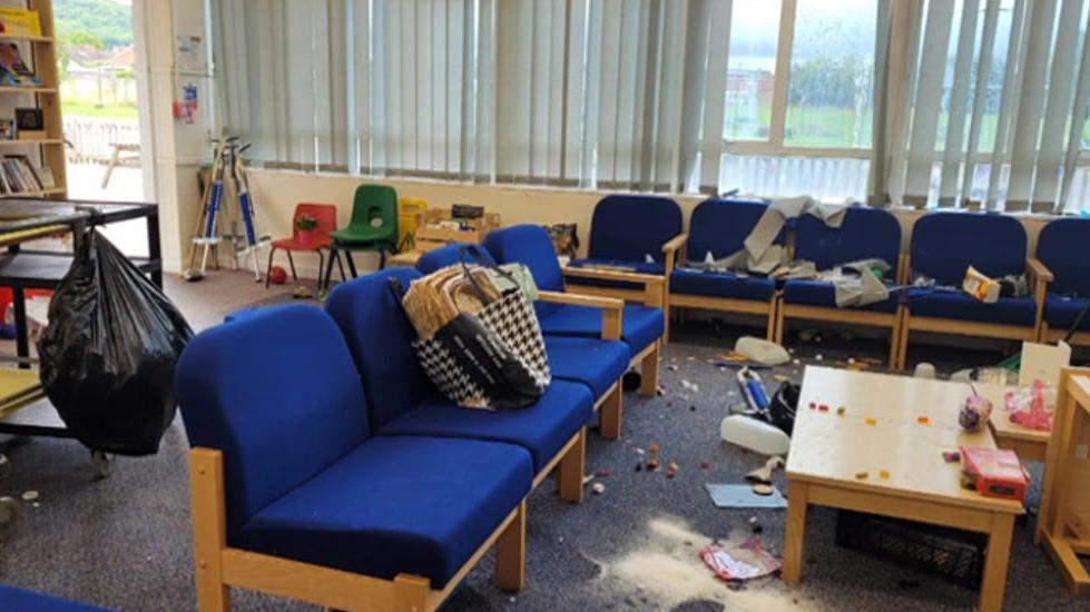 A staff room covered in sawdust, empty milk bottles, and rubbish