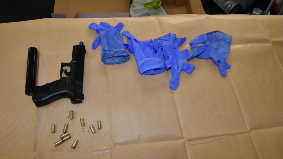 A black handgun and silencer with bullets and four gloves