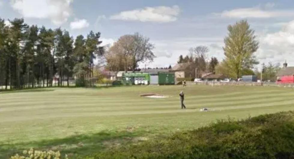 A golf course with a bunker and a golfer mid-swing