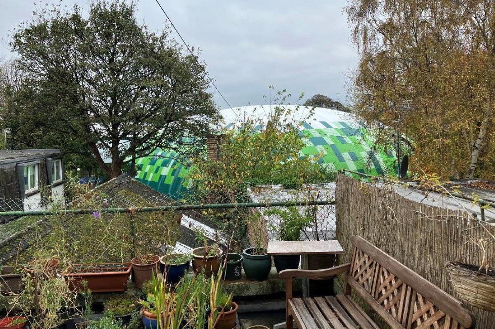 A balcony garden with the inflatable tennis court in the background.