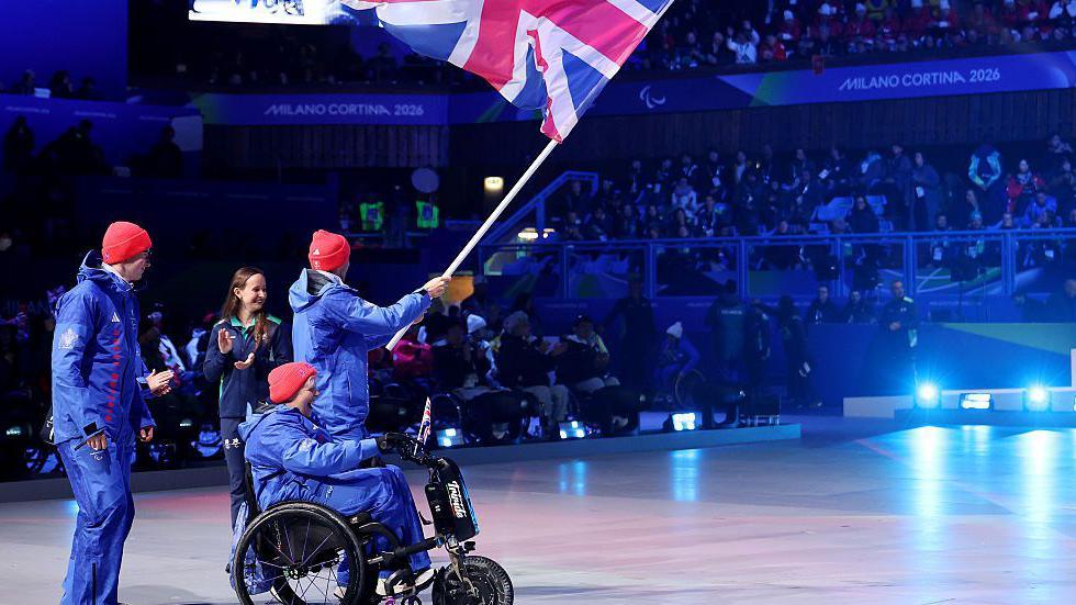 The Great Britain flag is brought into the Winter Paralympic ceremony by Para-skiers Neil Simpson and Rob Poth and wheelchair curler Jo Butterfield