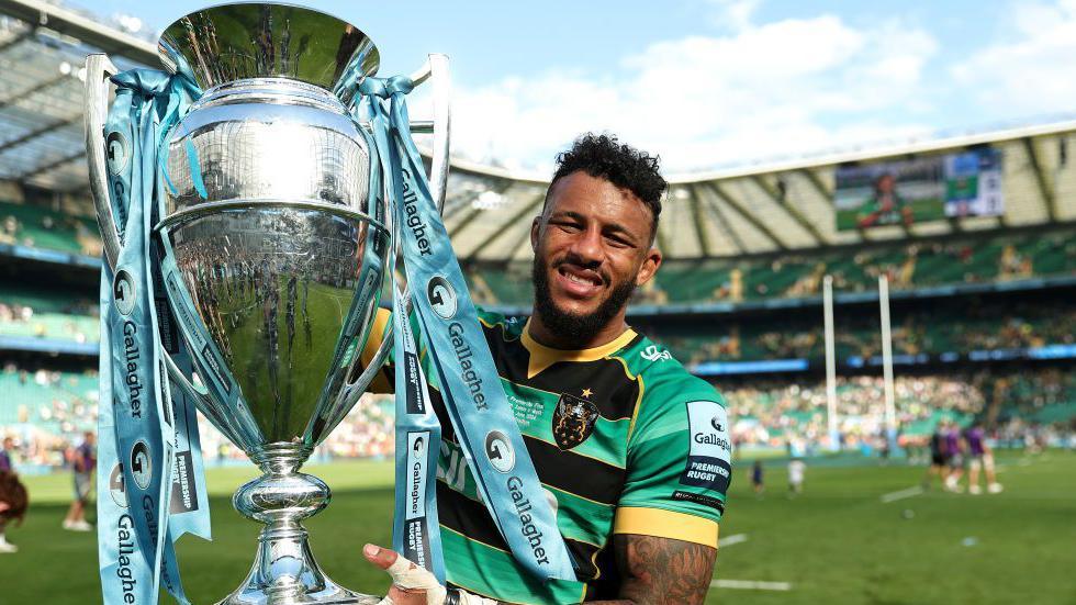 Courtney Lawes holds the Premiership trophy on the Twickenham pitch following Northampton Saints' win over Bath in June.  