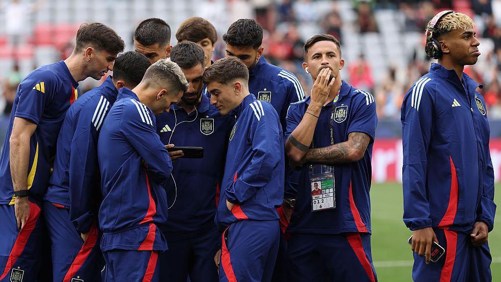 Spain players look at a phone