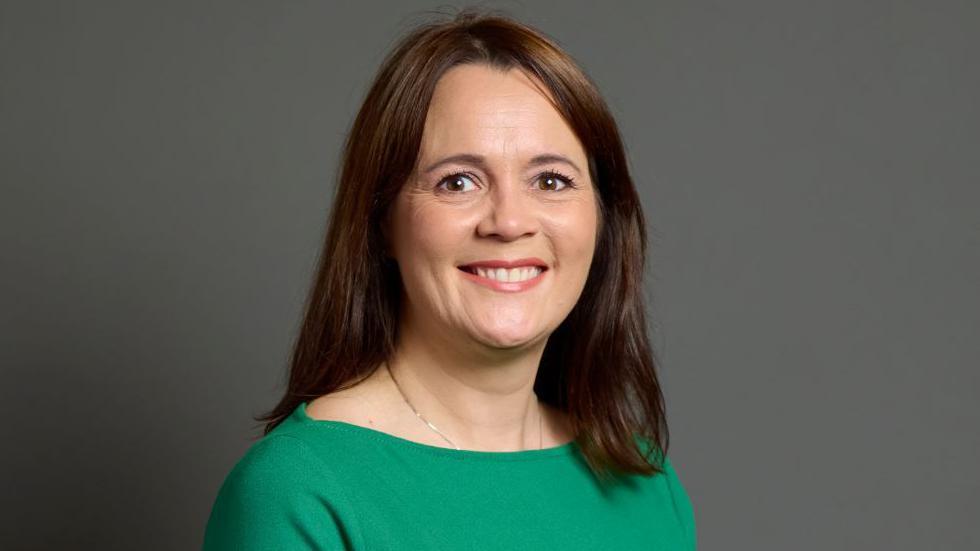 Portrait of Lindsay Farnsworth - she has brown hair and is wearing a green dress