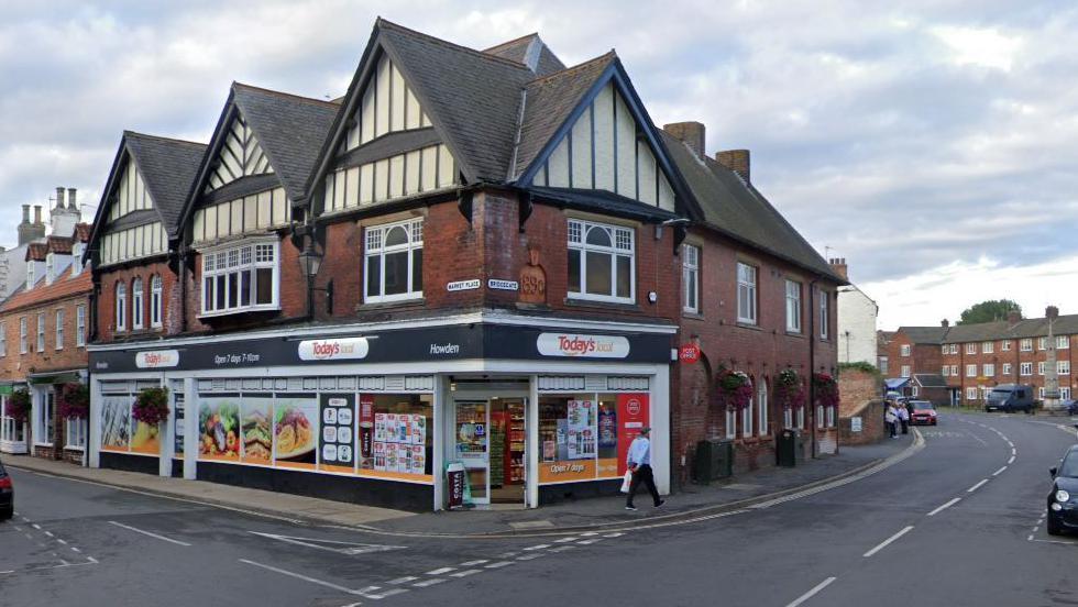 Google street view of a forked road. On the corner is a convenient store