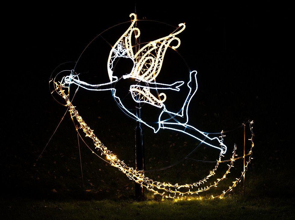 An illuminated fairy against the night sky.