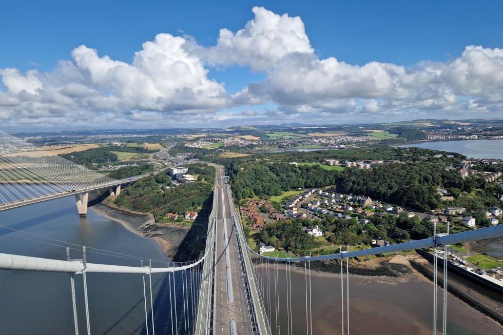 Steelwork on the Forth Road Bridge with the sea and houses and trees below