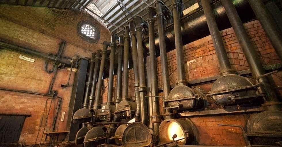 Inside a red brick building are lots of pipes and small furnaces which make up Fakenham Gas Works