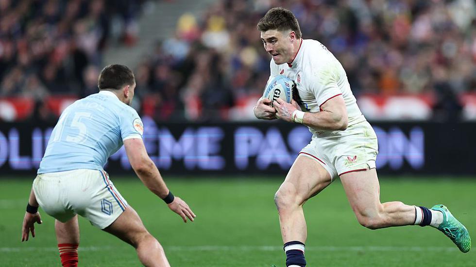 Tommy Freeman carries the ball under his right arm as France full-back Tomas Ramos prepares to make a tackle