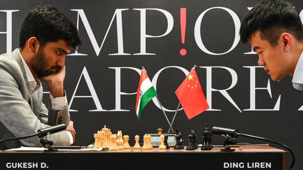 China's chess grandmaster Ding Liren (R) and India's chess grandmaster Gukesh Dommaraju (L) compete during the start of the FIDE World Chess Championship in Singapore on November 25, 2024. 