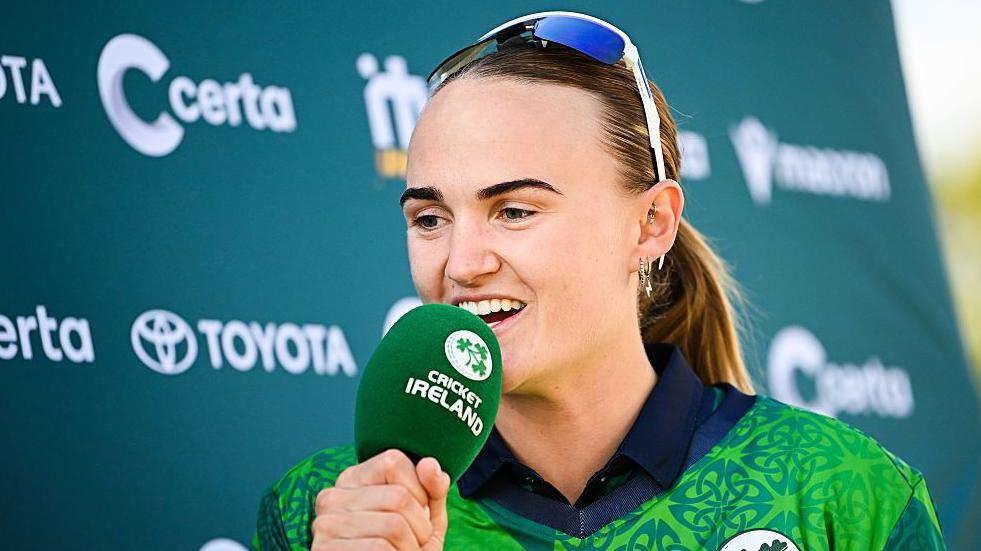 Gaby Lewis being interviewed holding a Cricket Ireland microphone after an international with Pakistan