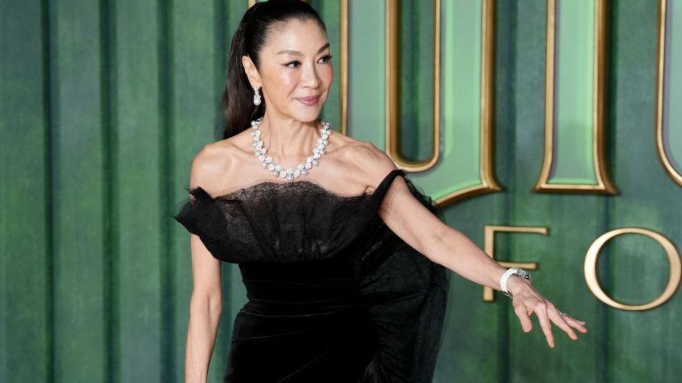Michelle Yeoh dressed in black is pictured against a green background arriving for the European premiere of Wicked: For Good, at Cineworld Leicester Square in London. 