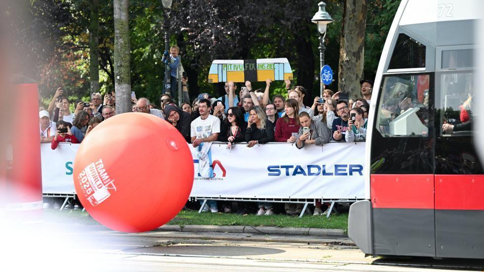 A tram approaches a large red ball, which it is intending to hit into large inflatable pins