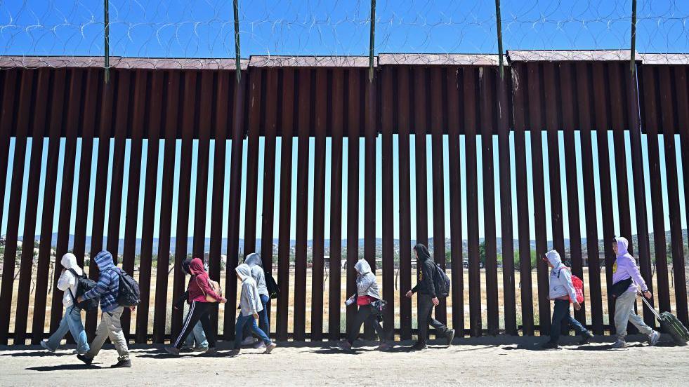 Migrants walk on the US side of the border wall in Jacumba Hot Springs, California. Photo: June 2024 
