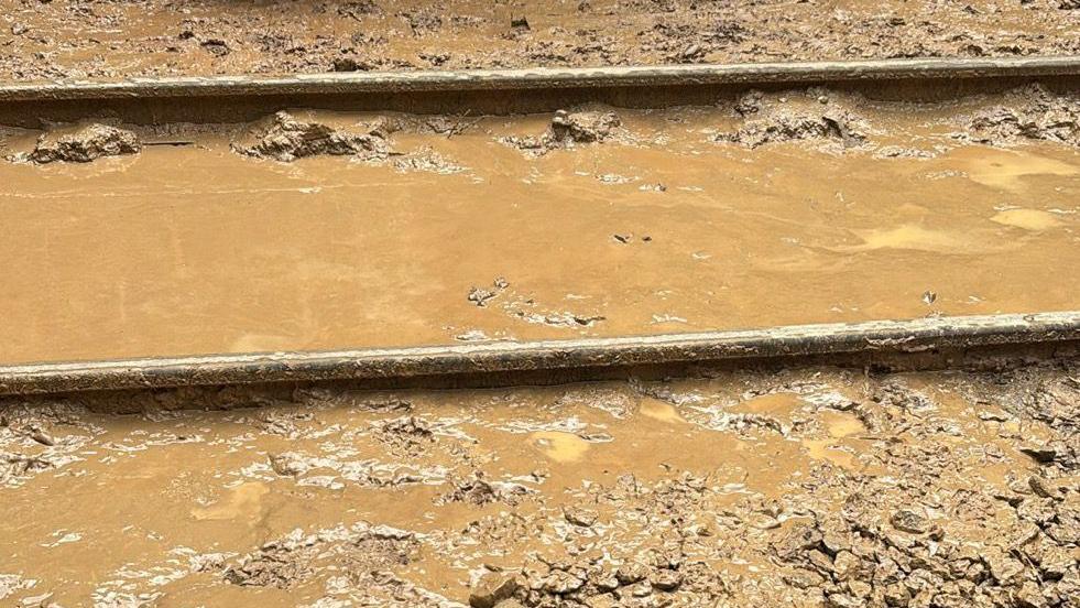 A train track swamped in brown thick mud